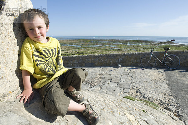 Junge lehnt an Steinmauer  Portrait