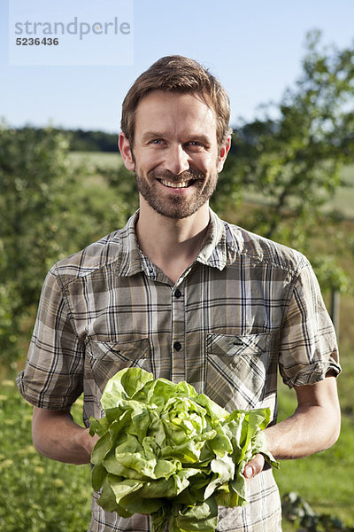 Mann mit Salatkopf im Freien
