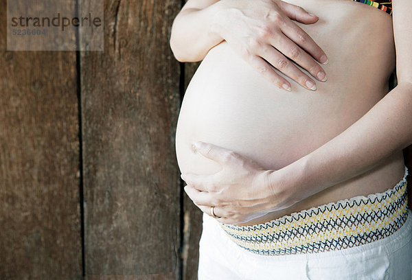 Schwangere Frau  die ihren Bauch hält.