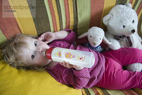 Baby Mädchen liegend  Milch aus der Babyflasche trinkend