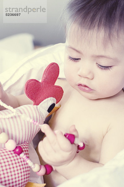 Kleines Mädchen spielt mit einer Spielzeugkette