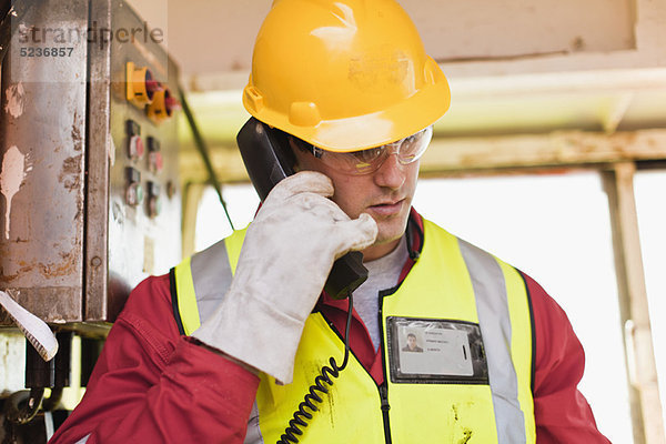 Arbeiter telefoniert auf der Bohrinsel