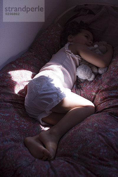 Kleines Mädchen auf dem Bett liegend