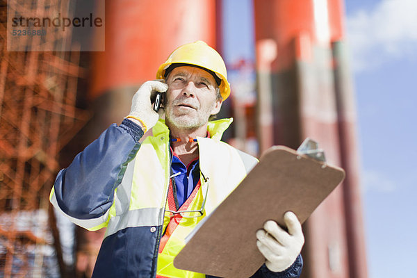 Arbeiter im Gespräch auf dem Handy auf der Bohrinsel