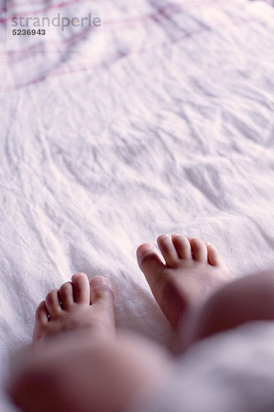 Fuß des Kindes auf dem Bett  Unterteil