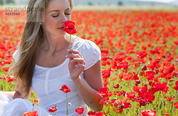 Frau riecht Mohn im Feld