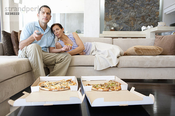 Paar essen Pizza im Wohnzimmer