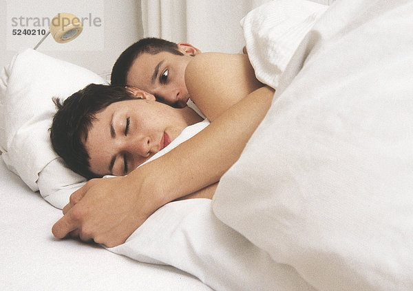 Paar liegt umarmt im Bett