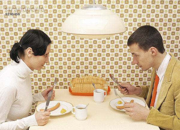 Paar sitzt am Küchentisch beim Essen  70er Jahre Nostalgie