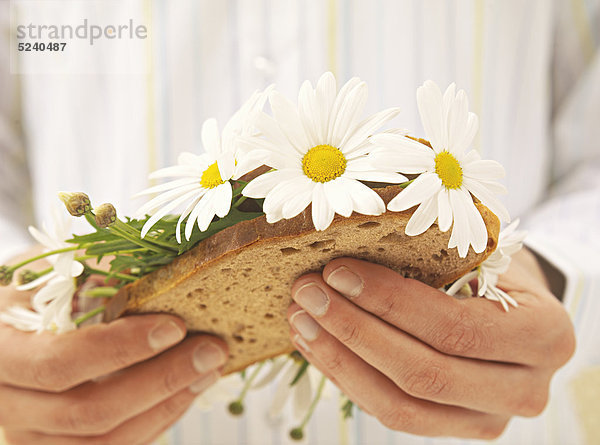Mann hält Brot mit Margeritenblumen  Detail
