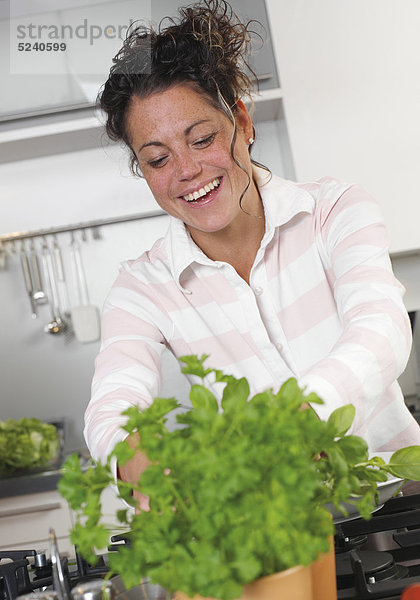 Frau in der Küche an Kräutertöpfchen