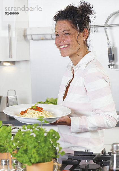 Frau mit einem Teller Spagetti in der Küche