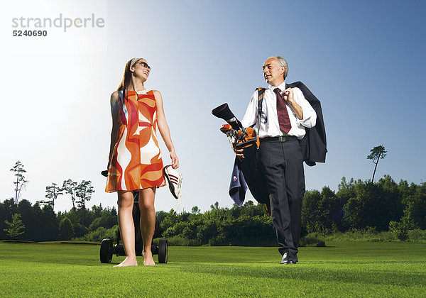 Älterer Manager und junge Frau auf Golfplatz