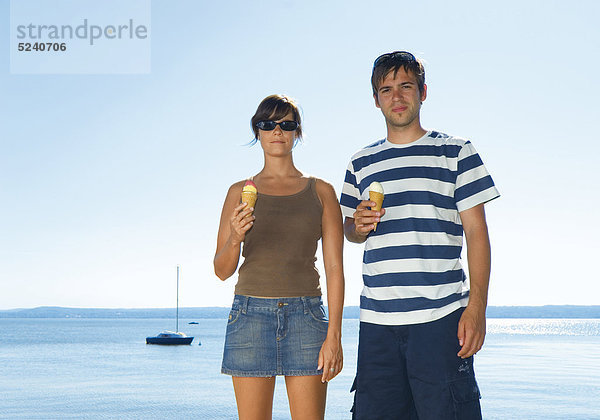Junges Paar  stehen mit Eistüten an See