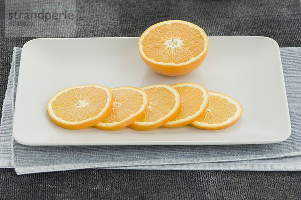 Halbe Orange mit Scheiben auf dem Teller  Nahaufnahme