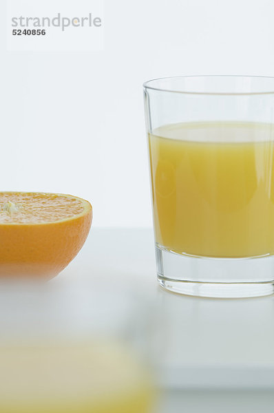 Glas Orangensaft mit halber Orange auf dem Tisch  Nahaufnahme