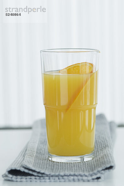 Glas Orangensaft mit Orangenscheibe auf Serviette