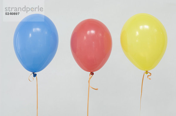 Mehrfarbige Luftballons in Reihe vor weißem Hintergrund  Nahaufnahme