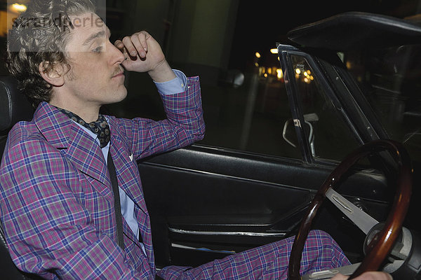 Mann fährt klassisches Cabriolet bei Nacht