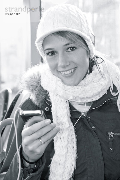 Junge Frau mit Mütze  Schal und MP3-Player  Halbporträt