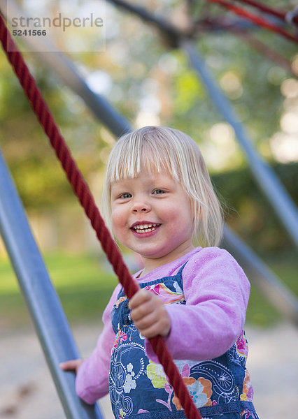 Mädchen klettern auf Klettergerüst im Spielplatz  lächelnd  Portrait