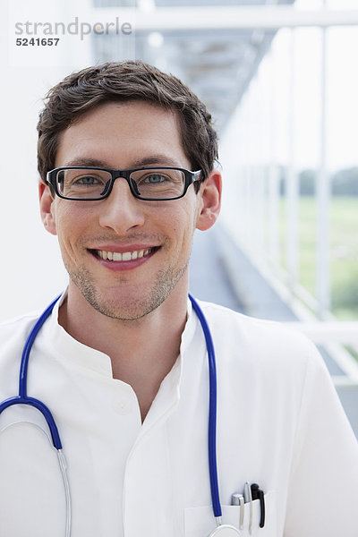 Deutschland  Bayern  Diessen am Ammersee  Nahaufnahme eines jungen Arztes mit Stethoskop  lächelnd  Portrait