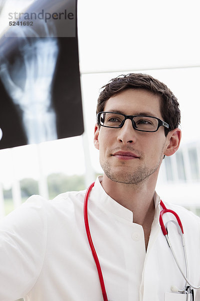 Deutschland  Bayern  Diessen am Ammersee  Junger Arzt beim Röntgen  Lächeln  Nahaufnahme