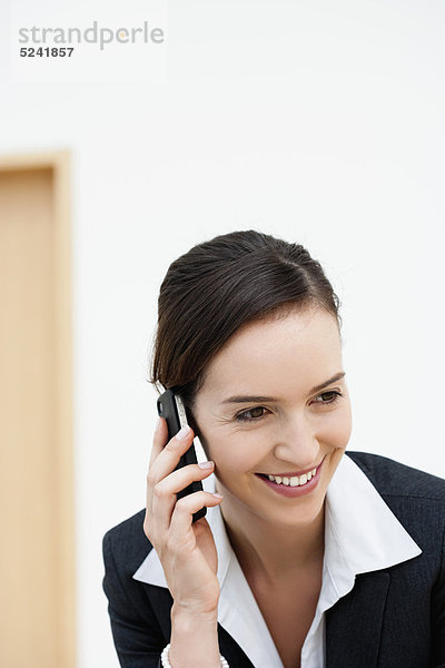 Diessen am Ammersee  Junge Geschäftsfrau im Gespräch mit dem Handy  lächelnd