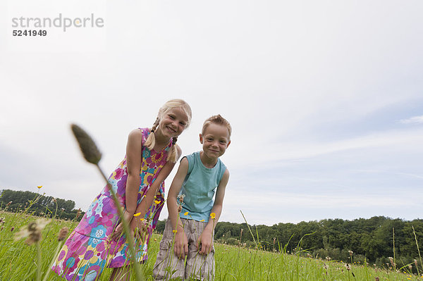 Deutschland  Nordrhein-Westfalen  Hennef  Junge und Mädchen auf der Wiese beim Blumenschauen