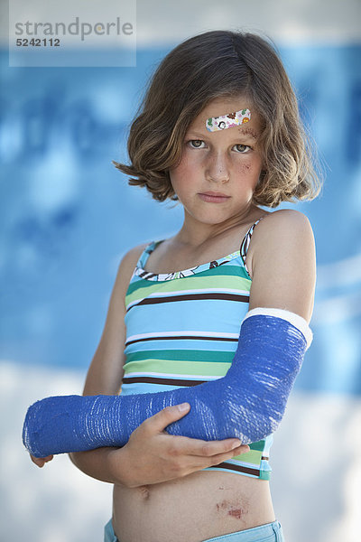 Verwundetes Mädchen in Badebekleidung und mit gebrochenem Arm  Portrait
