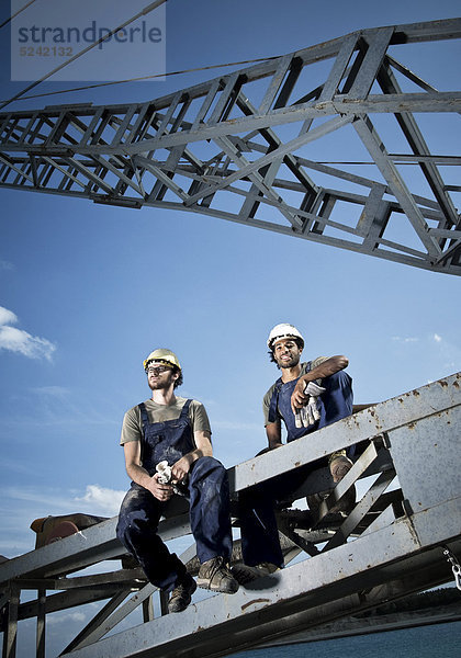 Zwei Arbeiter sitzen auf Stahlkonstruktion