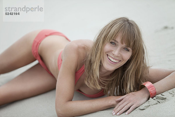 Junge Frau in Strandkleidung am Strand liegend  Portrait