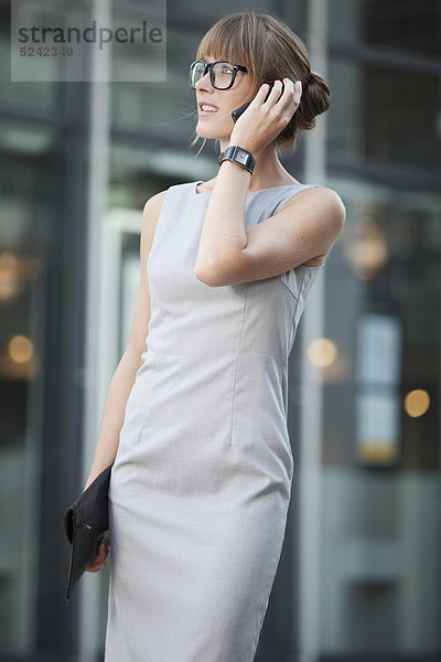 Junge Geschäftsfrau mit Brille per Handy