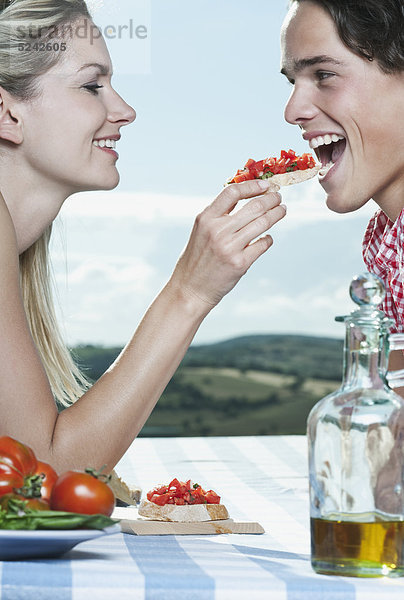Italien  Toskana  Junge Frau füttert Mann mit Snacks
