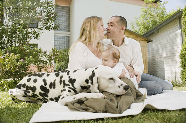 Deutschland  Bayern  Vater  Mutter und Tochter mit Dalmatiner im Garten  lächelnd