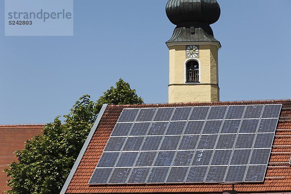 Deutschland  Bayern  Oberbayern  Frauenried  Blick auf Solarkollektor auf Dach und Kirchturm im Hintergrund
