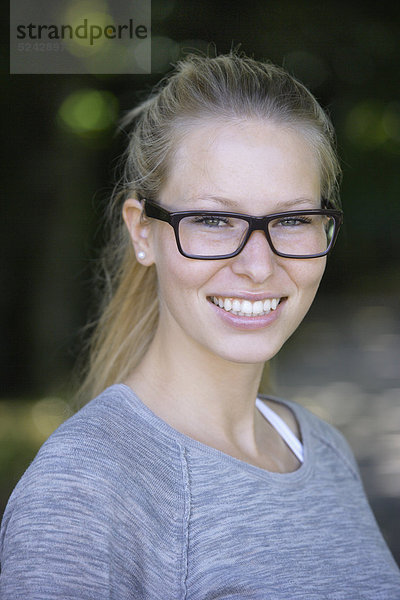 Junge Frau mit dicker Brille  lächelnd  Portrait  Nahaufnahme