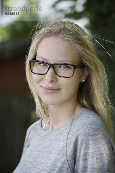 Junge Frau mit dicker Brille  lächelnd  Portrait  Nahaufnahme