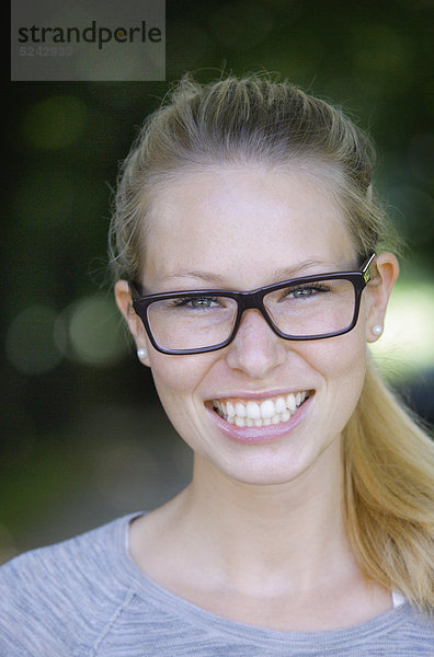 Nahaufnahme einer jungen Frau mit dicker Brille  Portrait  lächelnd