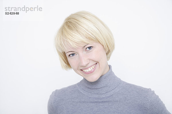 Nahaufnahme einer jungen Frau vor weißem Hintergrund  Porträt  Lächeln