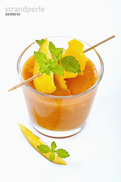 Nahaufnahme von Mango-Smoothie mit Minze und Mango-Scheibe auf weißem Hintergrund