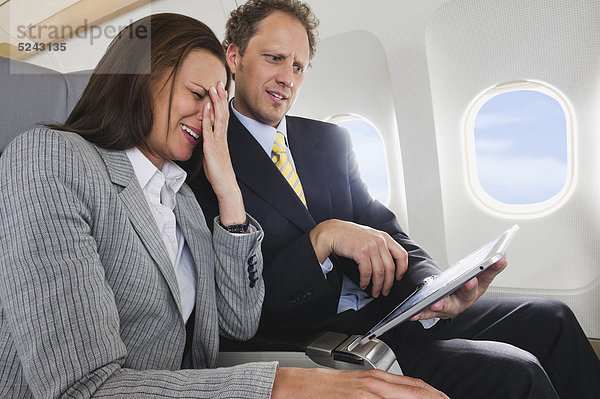 Geschäftsmann und Geschäftsfrau bei der Arbeit am ipad in der Business-Class-Flugzeugkabine