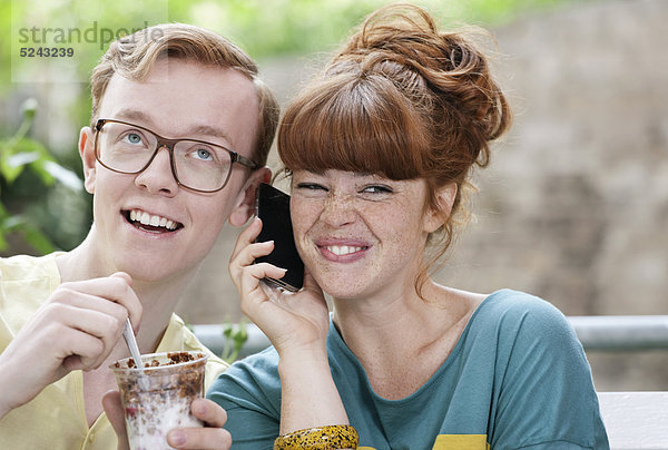 Deutschland  Berlin  Nahaufnahme eines jungen Paares  das Handy hört  lächelnd