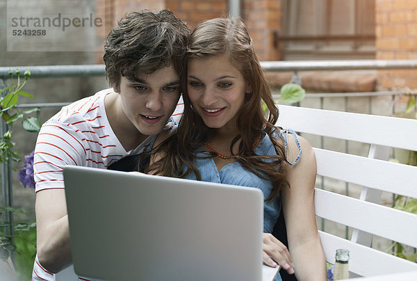 Nahaufnahme eines jungen Mannes und einer jungen Frau am Laptop  lächelnd