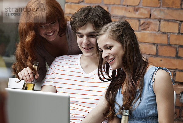 Junge Männer und Frauen mit Laptop  lächelnd