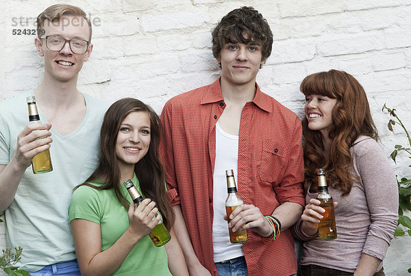 Junge Männer und Frauen  die Bierflaschen halten  lächelnd