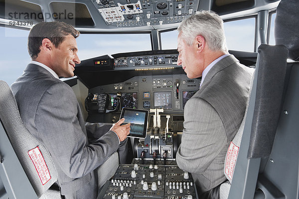Deutschland  Bayern  München  Geschäftsleute mit digitalem Tisch im Flugzeugcockpit
