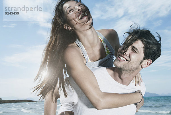 Spanien  Mallorca  Junger Mann mit Frau auf dem Rücken am Strand
