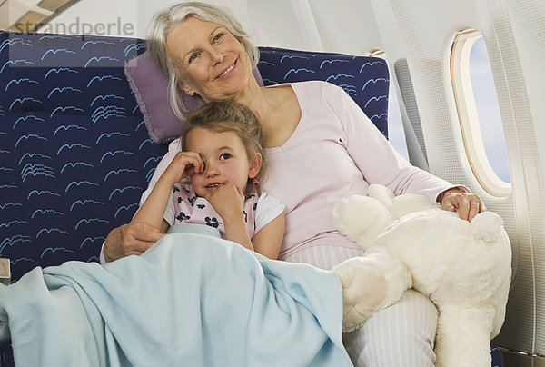 Seniorin und Seniorin entspannt am Fenster im Economy Class Flugzeug