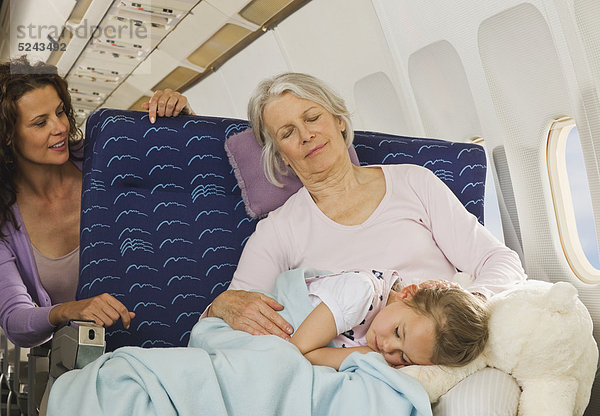 Seniorin und Seniorin schlafen neben dem Fenster im Economy Class-Flugzeug